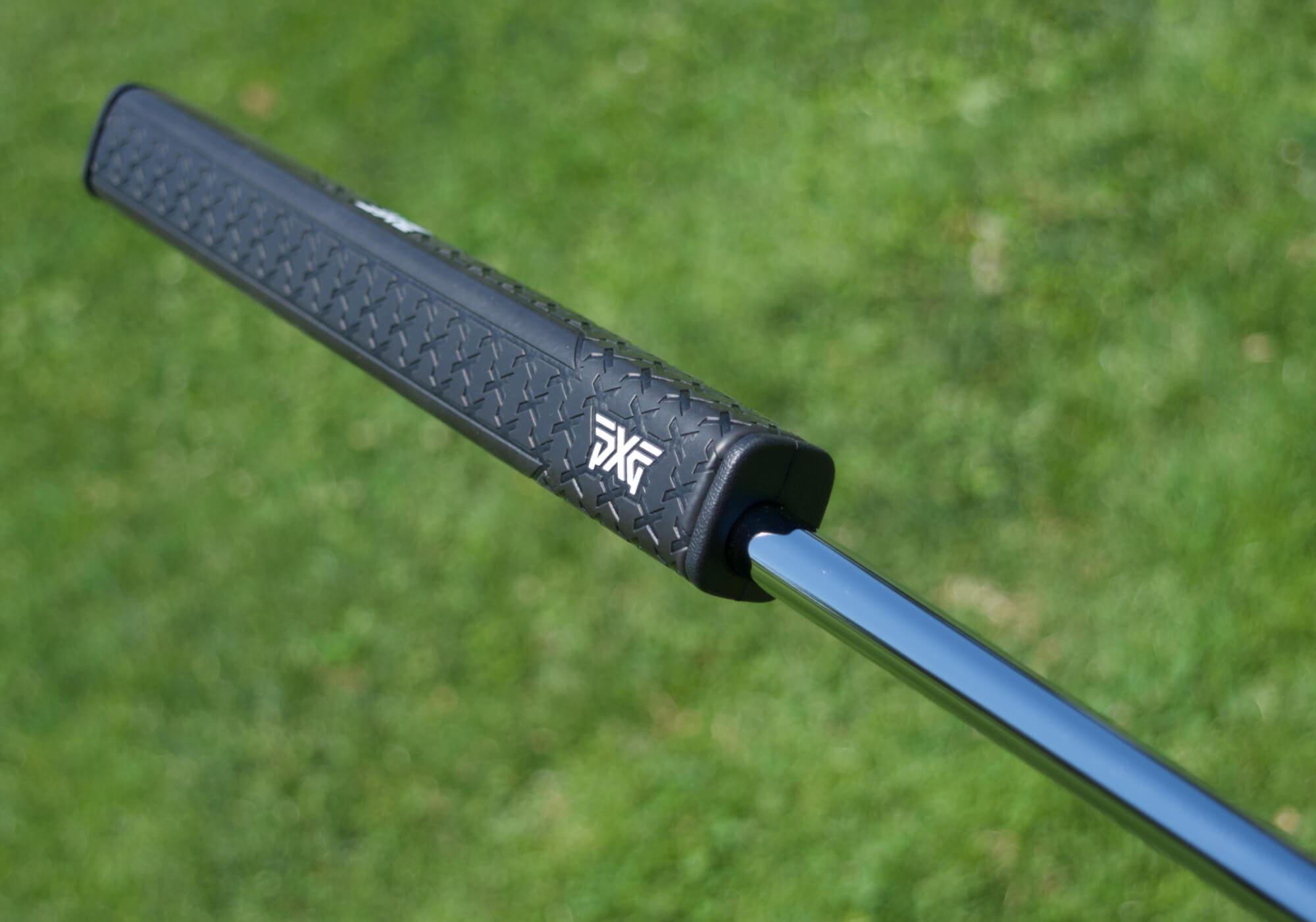 PXGのロゴが大きくデザインされたブラックのパター用ヘッドカバーを手に持った様子
