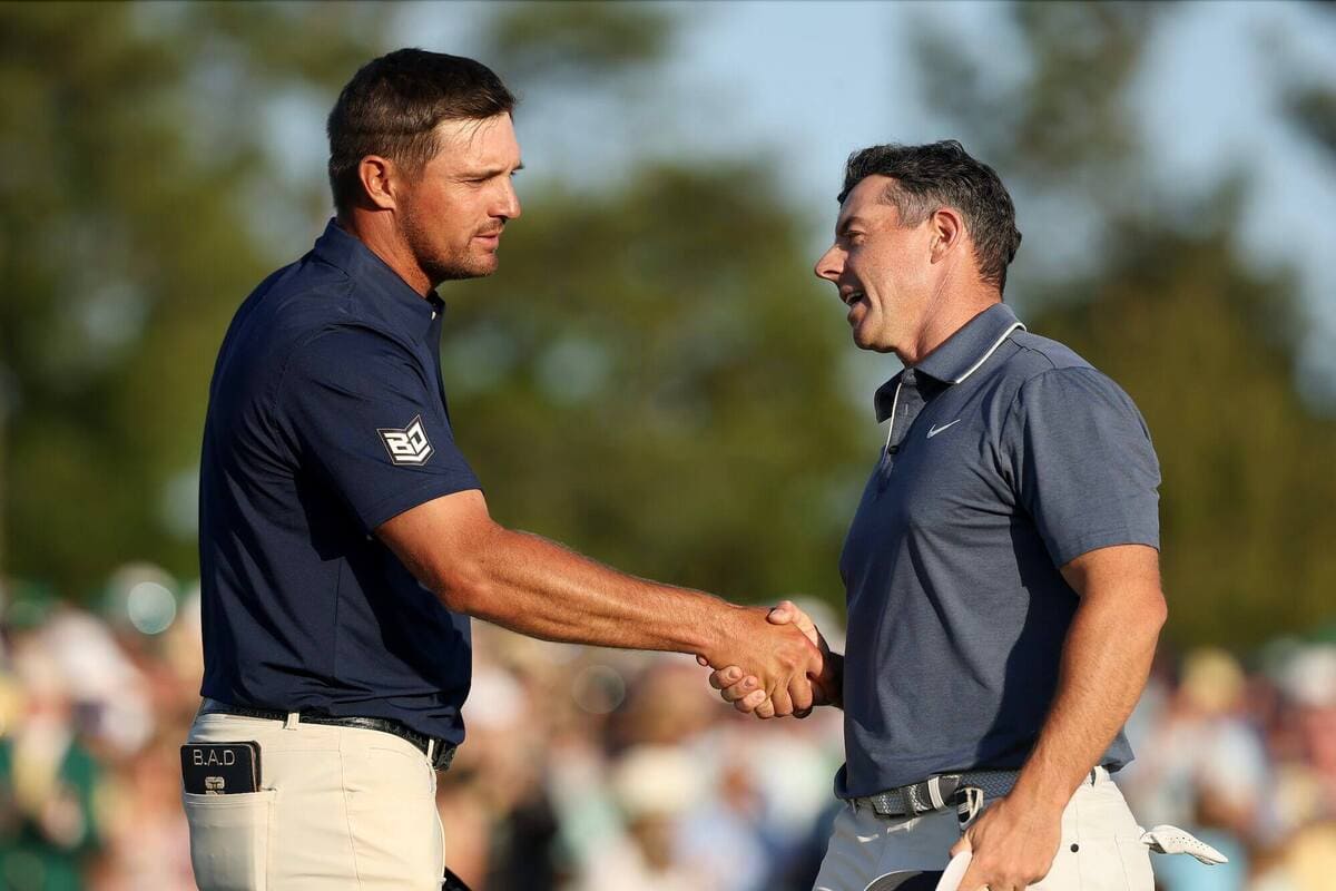 ローリー・マキロイとブライソン・デシャンボーが握手を交わす瞬間。ライダーカップ2025でのアメリカ代表とヨーロッパ代表を象徴するシーン。