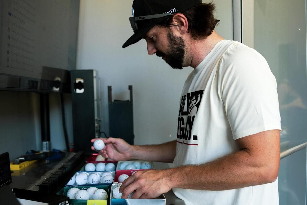 テスターが複数ブランドのゴルフボールを箱に並べ、テスト前に分類・整理している様子