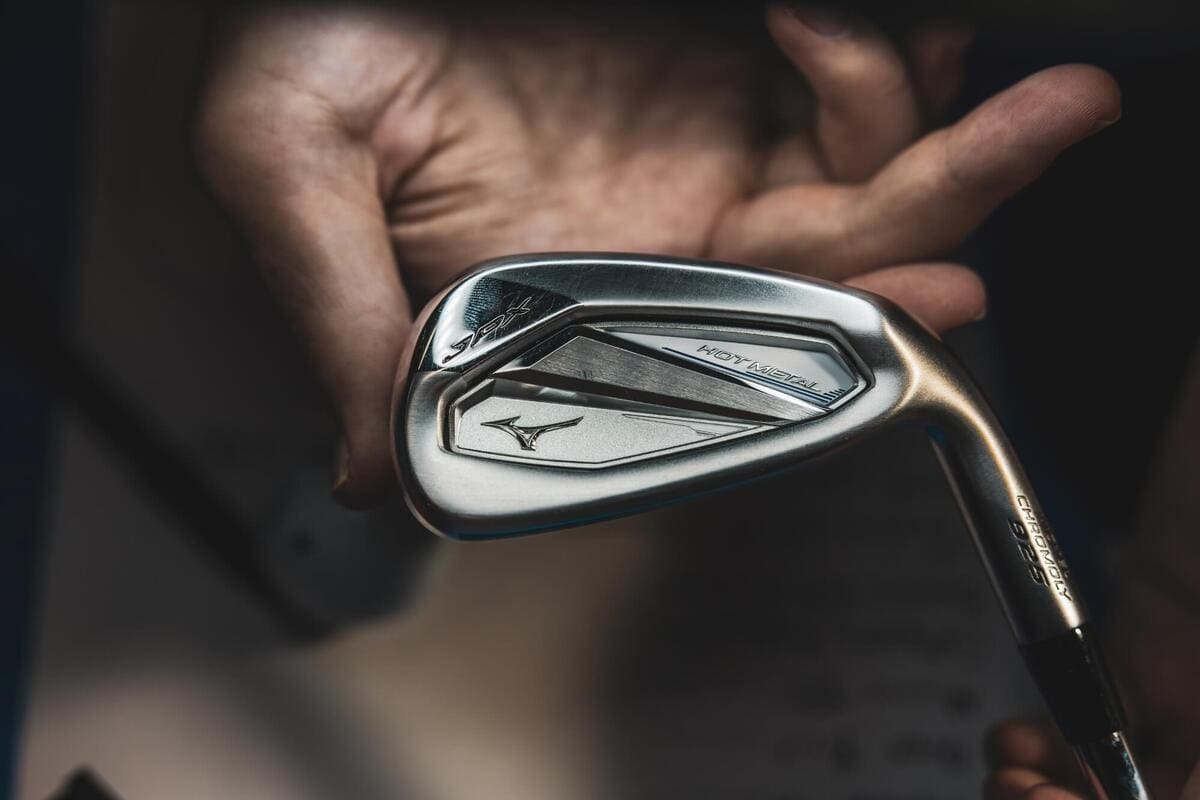 ミズノ「JPX 925 Hot Metal」アイアンを手に取る様子。ヘッドの立体構造とクロモリ素材の輝きが際立っている。