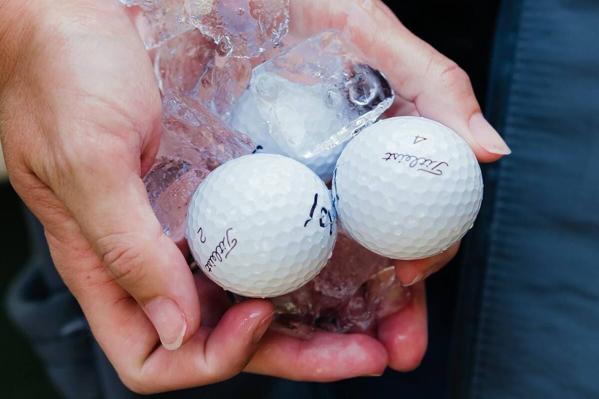 氷とともに冷却されたTitleistゴルフボールを手に持ち、温度変化による性能差を検証しているシーン
