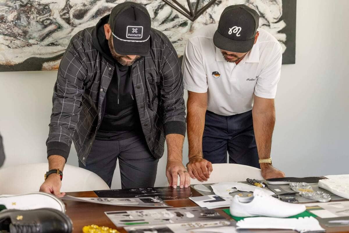 PAYNTR GOLFのデザインチームがゴルフシューズの設計資料とサンプルを確認しながら開発検討を行っている様子