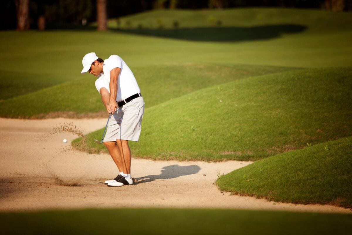 バンカーからクリーンにボールを打ち出す80台ゴルファーのショットシーン