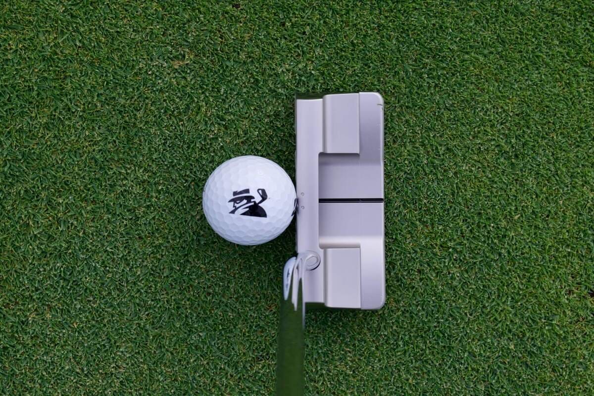 芝の上でゴルフボールと並べて構えた Evnroll ORIGIN ER2 パターを真上から撮影した写真。アライメントラインとボールとの位置関係が確認できる構図。