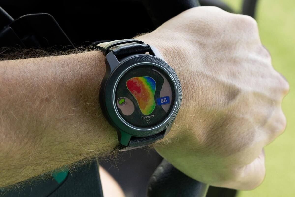 芝生の上に配置されたGPSゴルフナビ端末の集合カット。距離表示画面やコースマップ画面など、各デバイスの特徴が分かる構成。中央にMost Wantedロゴ。