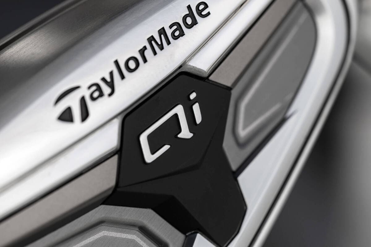 テーラーメイド「Qi Max」アイアンのQiロゴ周辺を拡大した写真。センターバッジとバックフェース素材の質感が確認できる