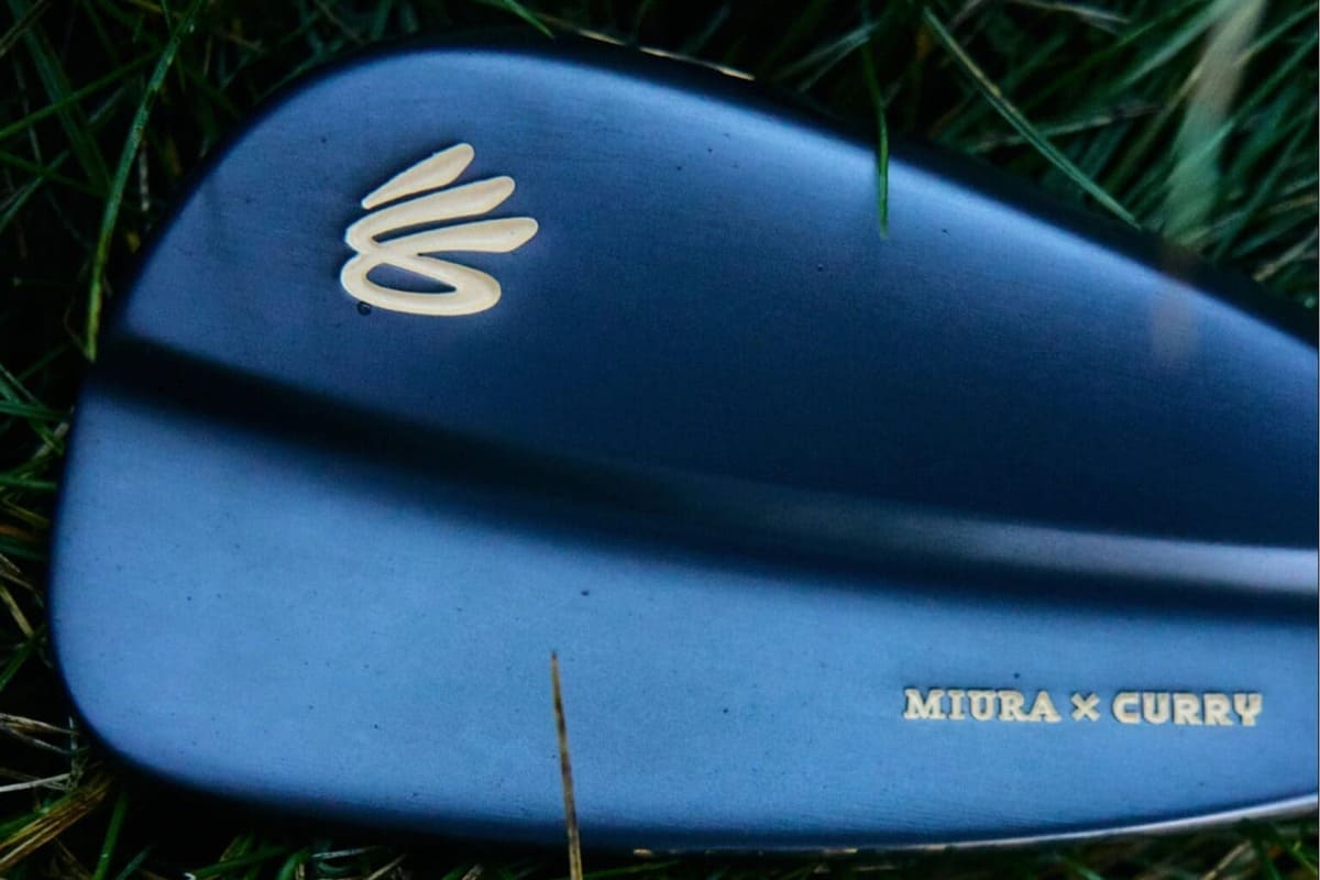 芝生の上に置かれたダークカラーのアイアンヘッド背面。金色のカリーロゴと「MIURA × CURRY」の刻印が見える。